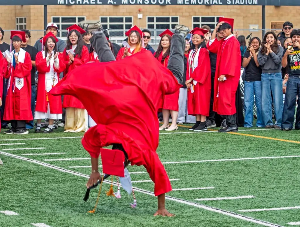Kenji Atuatasi completes a backflip as classmates smile during the...