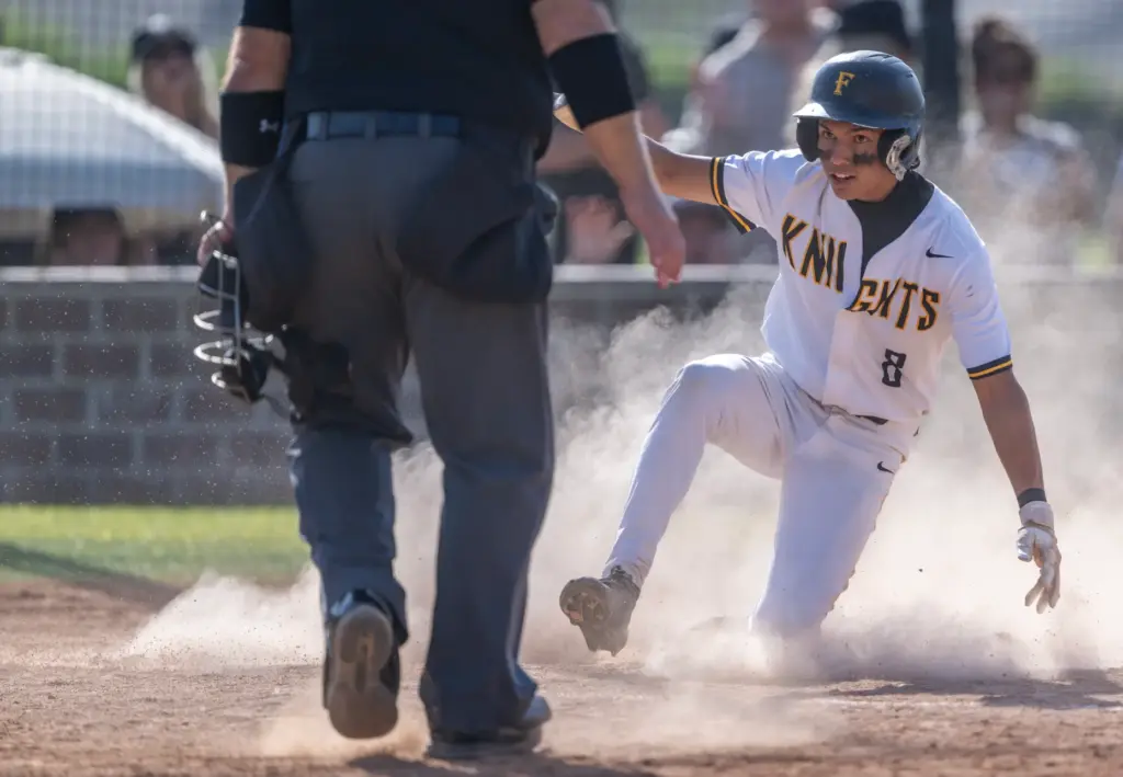 Foothill infielder Jason Gugino slides into home plate to score...
