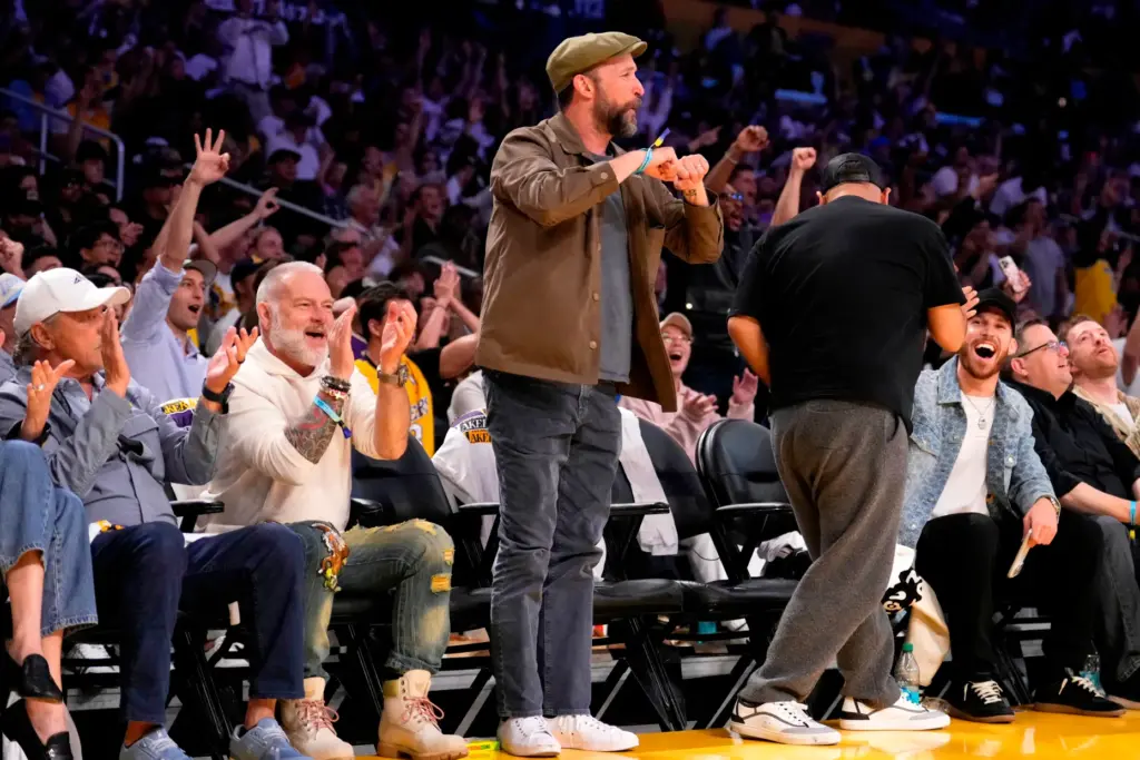Actor Noah Wyle, center, stands up to cheer during the...
