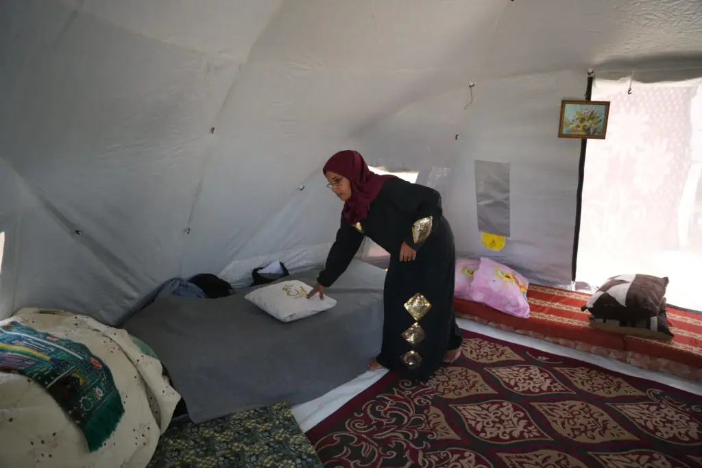 Majida Abu Jarad places a pillow on a bed inside the tent where she lives