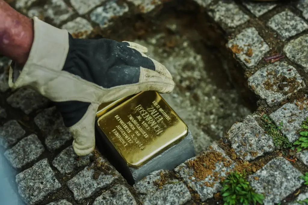 Artist Gunter Demnig places a palm-sized brass Holocaust plaque