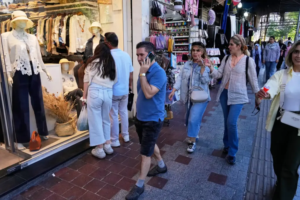 People walk along a sidewalk in northern Tehran, Iran, Sunday,...