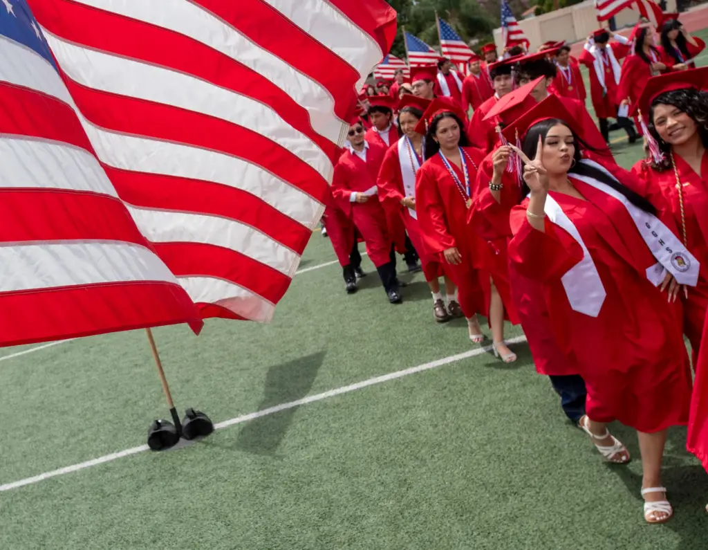 Graduates waves to the crowd as the march into the...