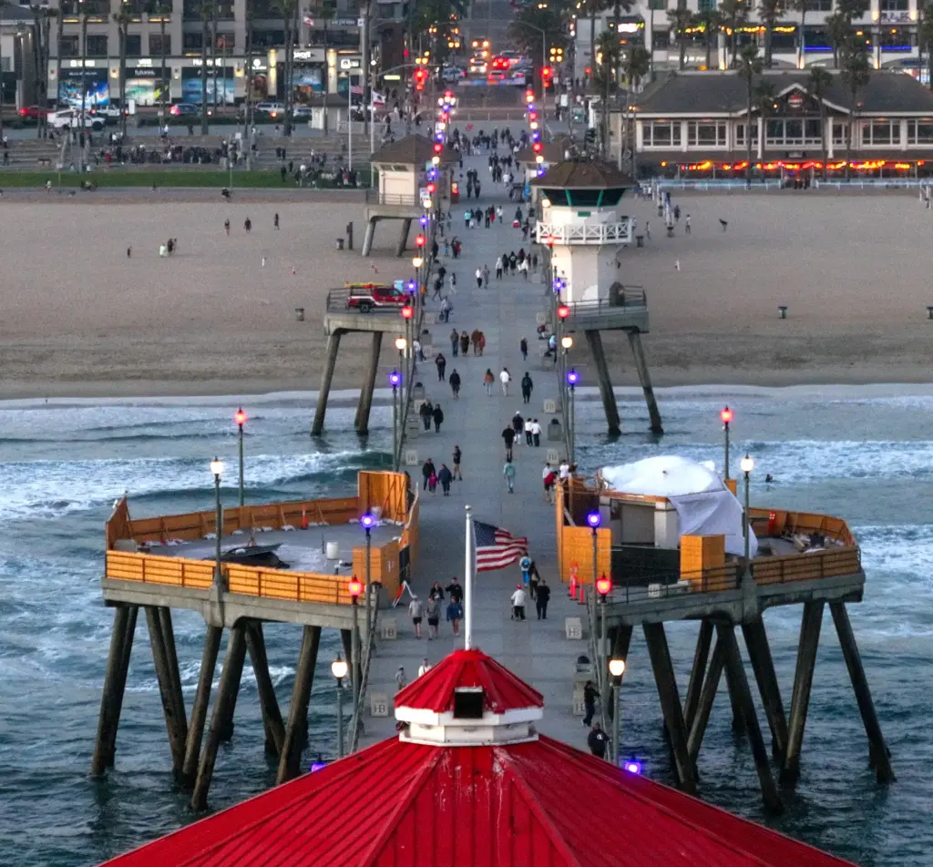 The Huntington Beach Pier is lit in red, white and...
