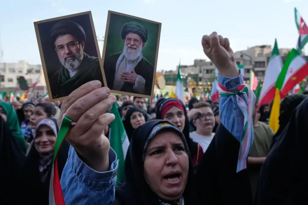 A woman holds up pictures of the Iranian Supreme Leader Ayatollah Mojtaba Khamenei and his father.