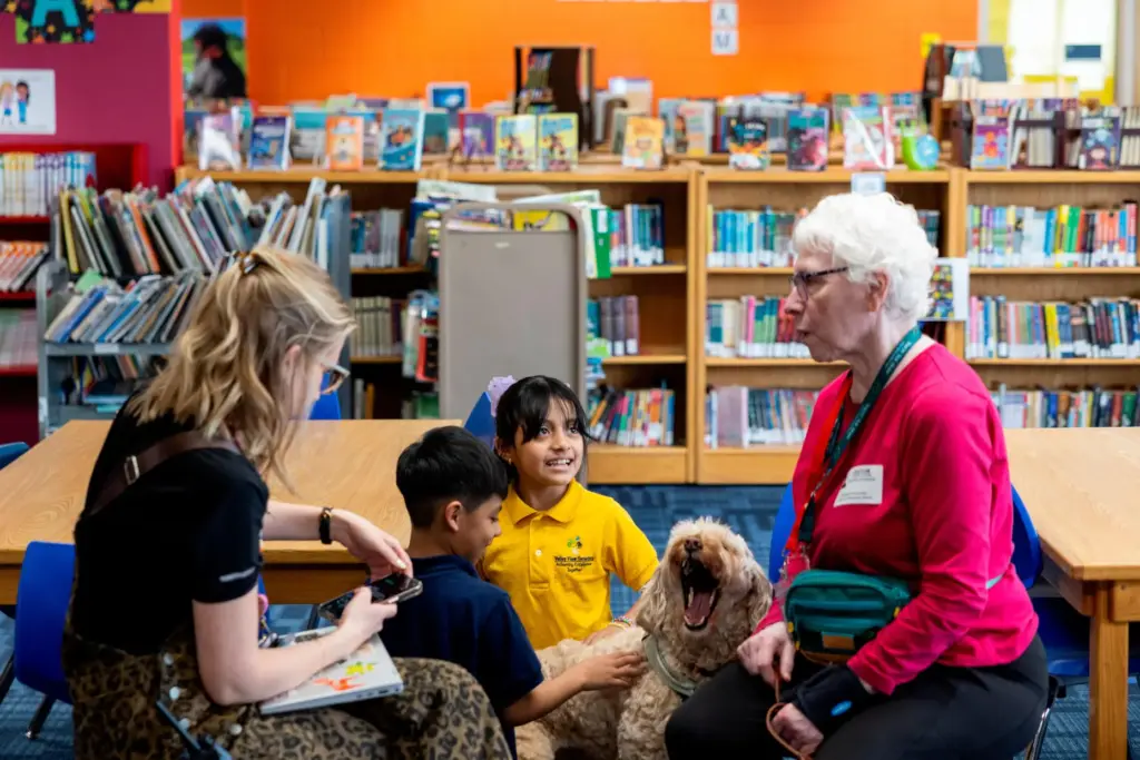 Yesli, center right, pets Sage, a therapy dog, at Valley...