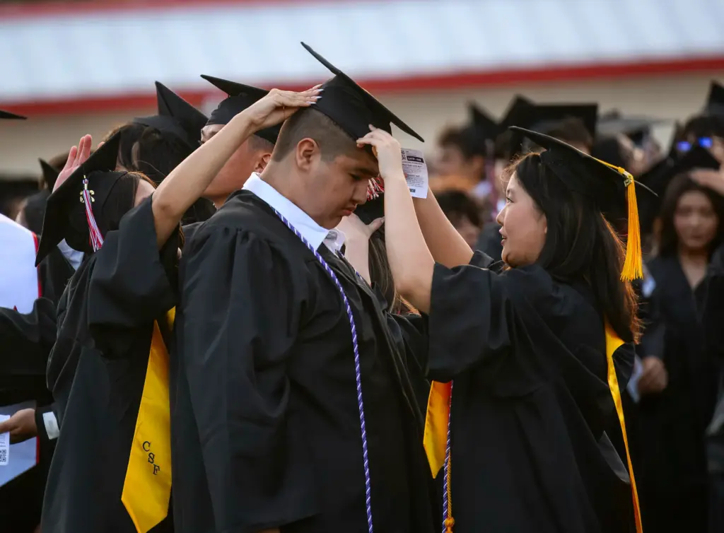 Paulina Lee, right, helps adjust the cap of a fellow...