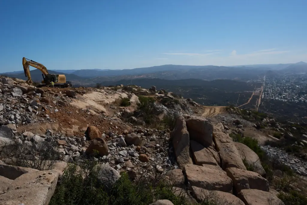Construction crews work on a new border wall segment on...
