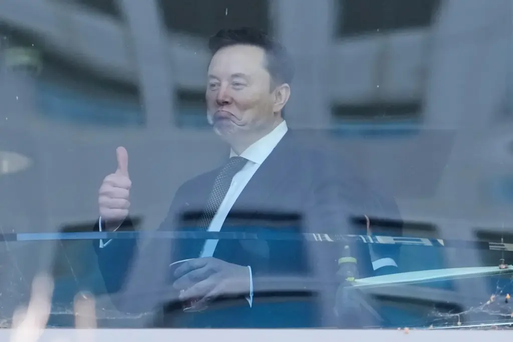 Elon Musk gestures as he walks through a hallway inside the U.S. District Court in Oakland.
