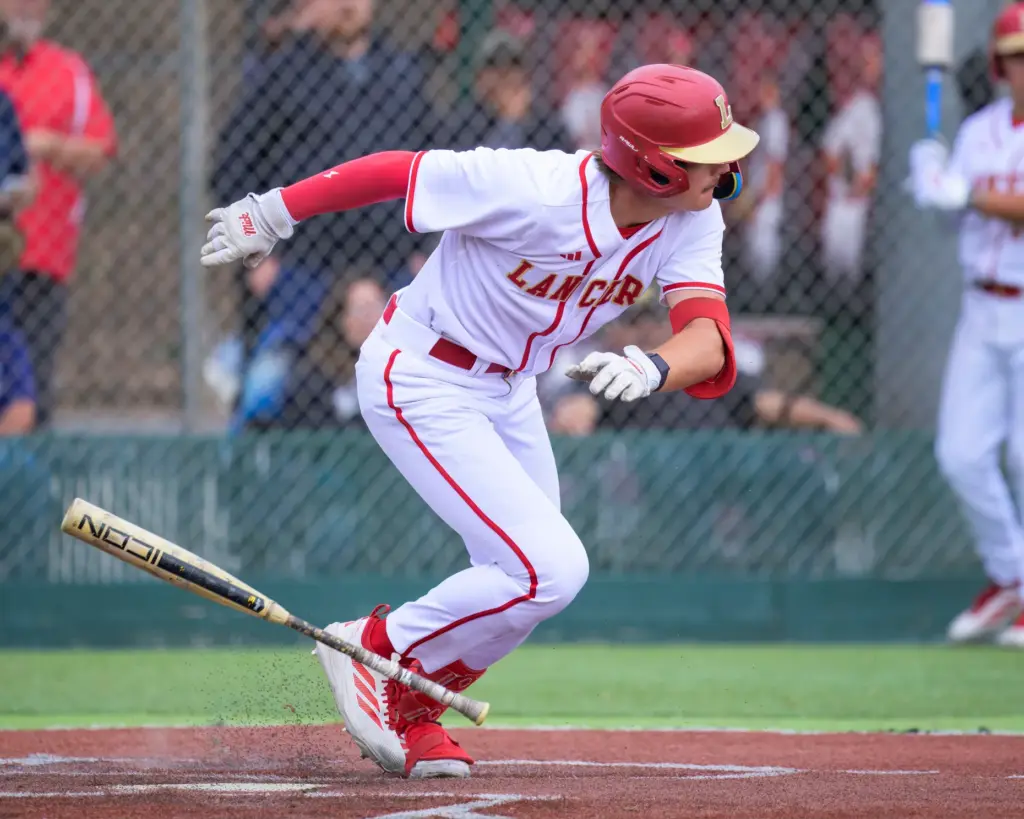 Orange Lutheran’s Trevor Deack starts to first after laying down...