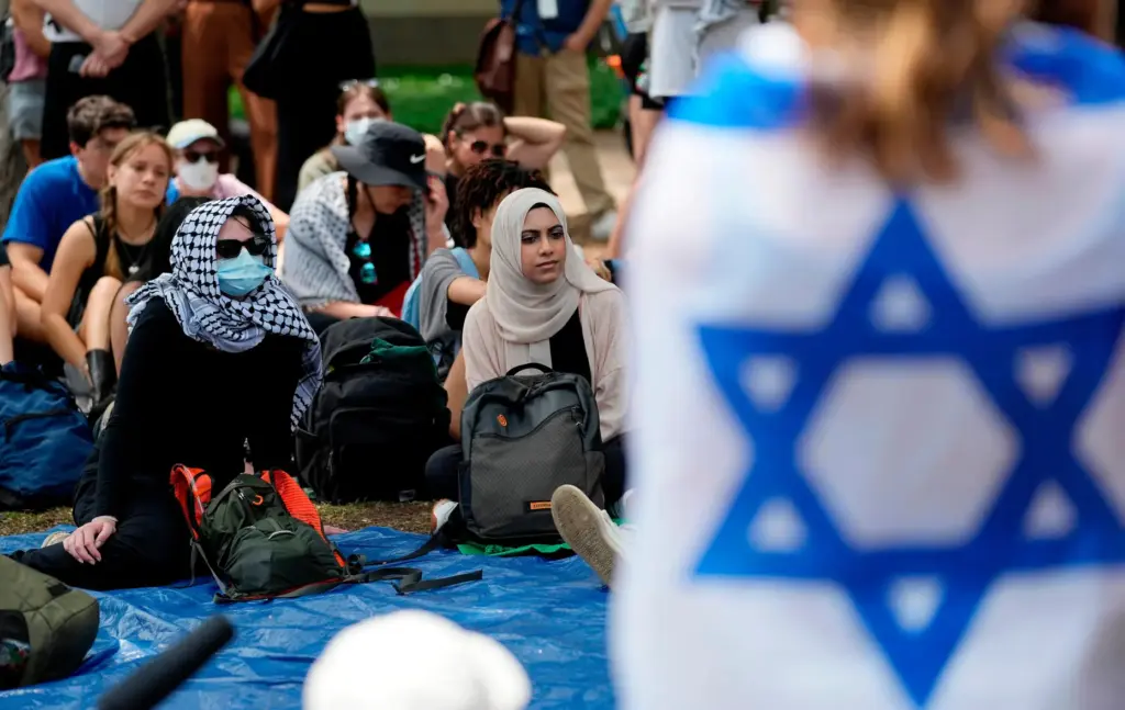 FILE – A student wrapped in an Israeli flag listens...