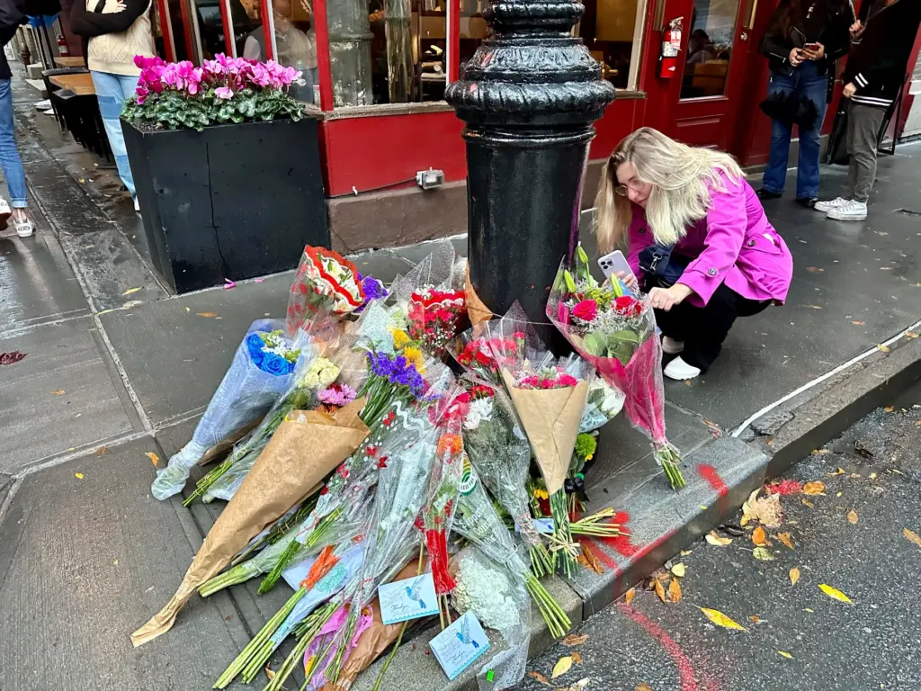 A person takes pictures of a makeshift memorial for Matthew...