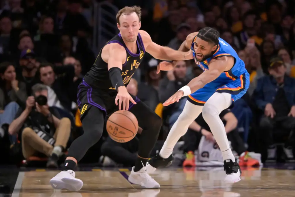Lakers guard Luke Kennard, left, shields the ball from the...