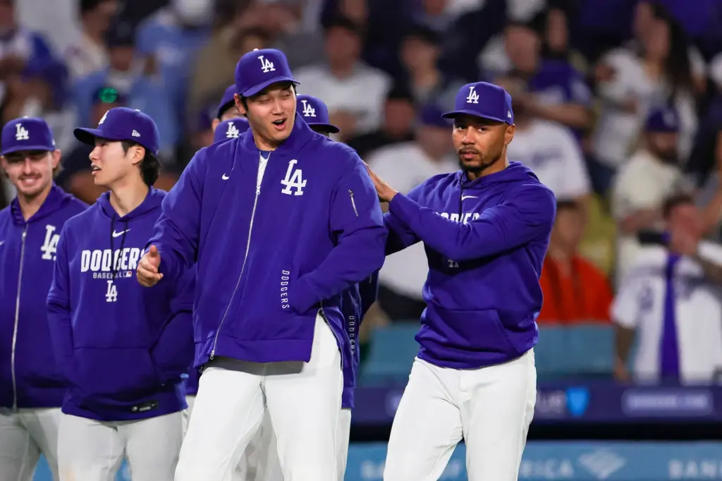 Dodgers star Shohei Ohtani, left, reacts to teammate Mookie Betts...