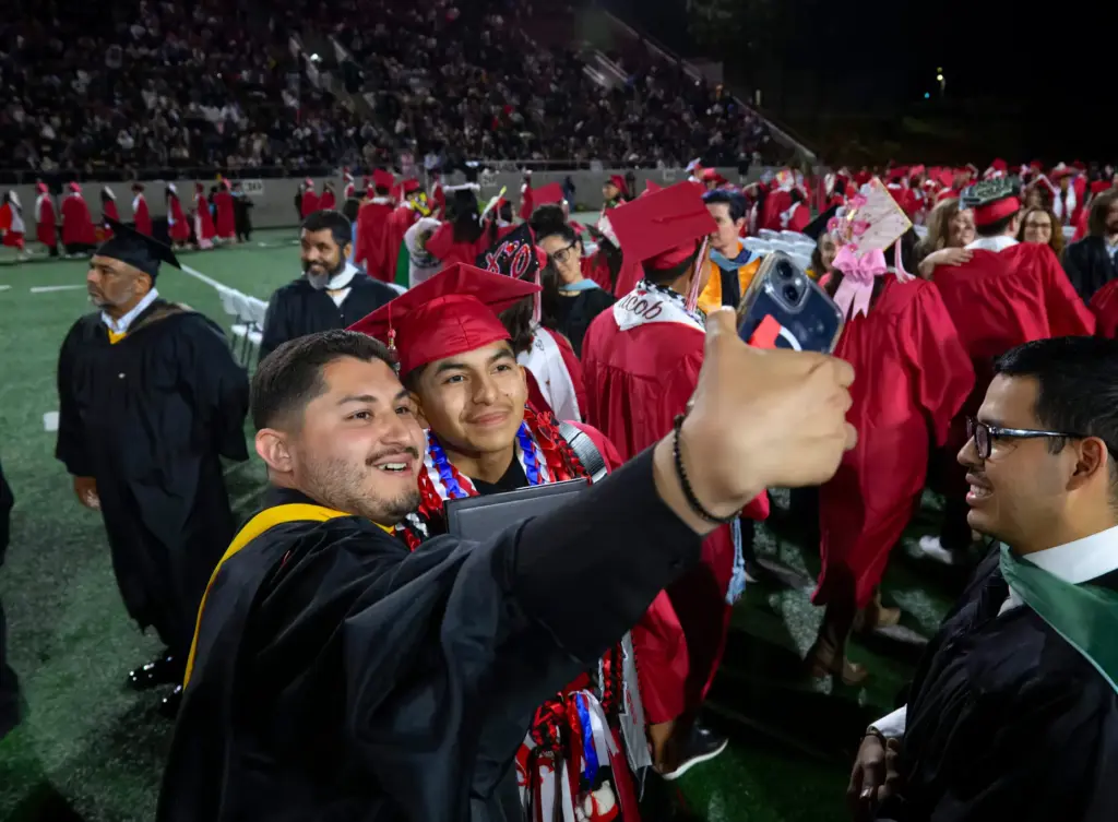 Graduate Tony Romero, center, gets a selfie taken by Carlos...