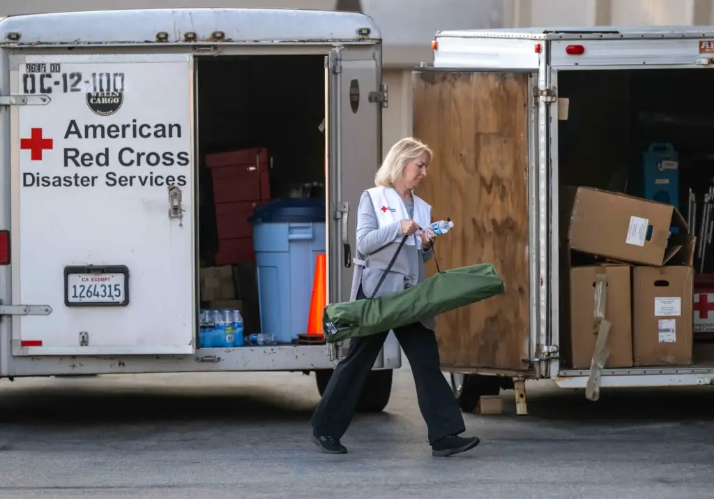 Tina Bartlett, an American Red Cross volunteer, retrieves a cot...