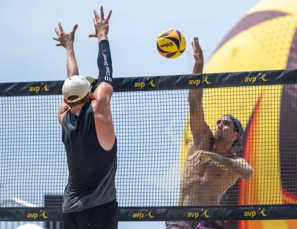 Trevor Crabb, right, hits the ball past a block attempt...
