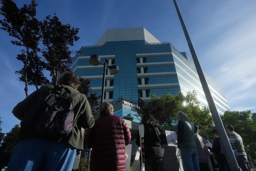 An interfaith community group holds signs while singing outside of...