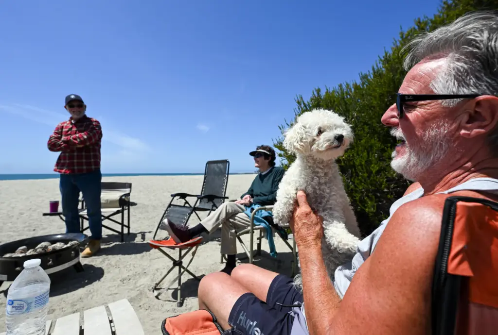John Taylor holds his dog, Millie, as he chats with...