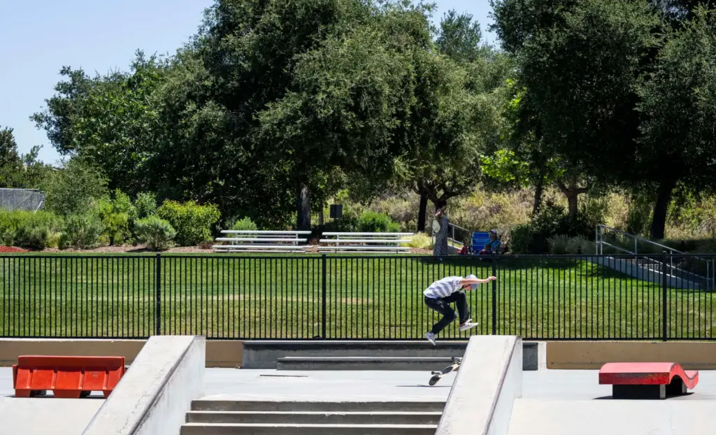 A skater practices in front of a grassy area at...