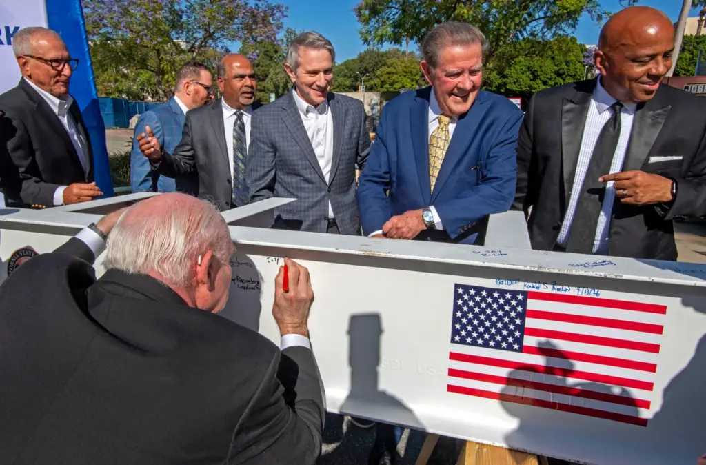 Dignitaries gather to have their photo made near a beam...