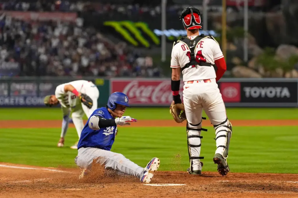 Dodgers’ Shohei Ohtani, center, scores for a three-run inside-the-park home...