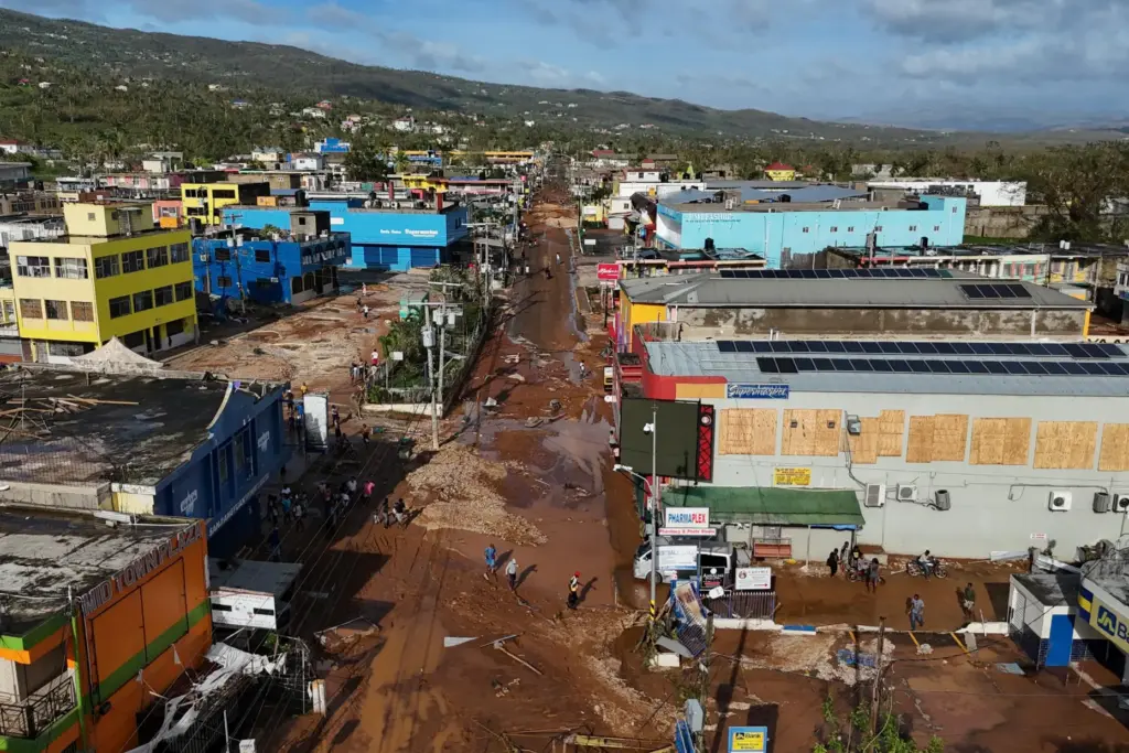 FILE – Residents walk through Santa Cruz, Jamaica, Oct. 29,...