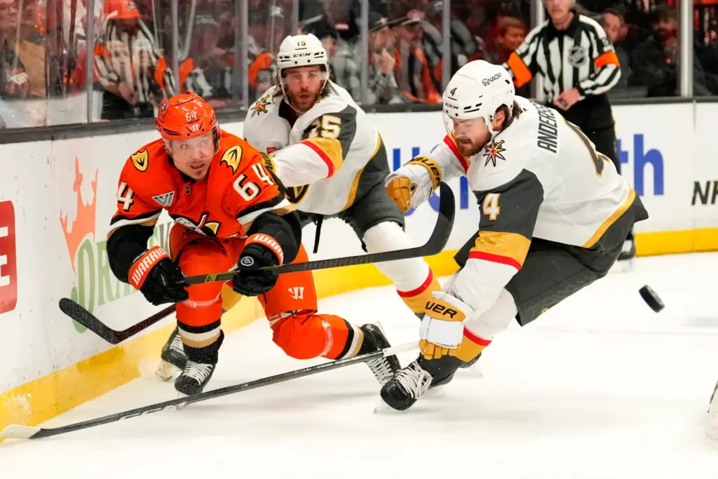 Ducks center Mikael Granlund, left, passes the puck while under...