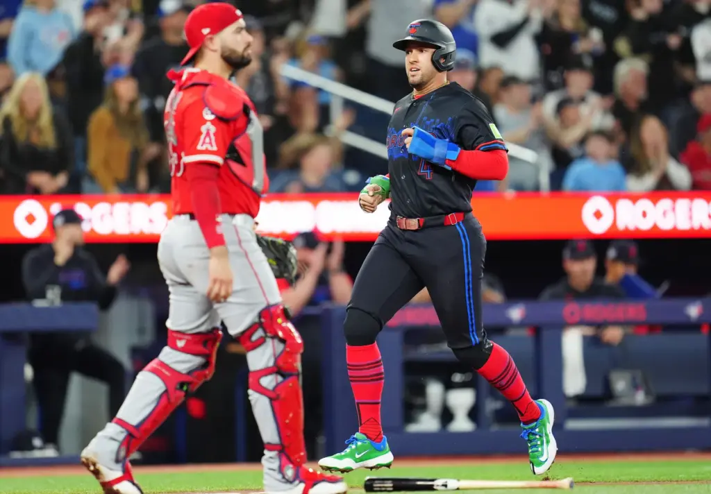 Toronto Blue Jays designated hitter George Springer, right, scores as...