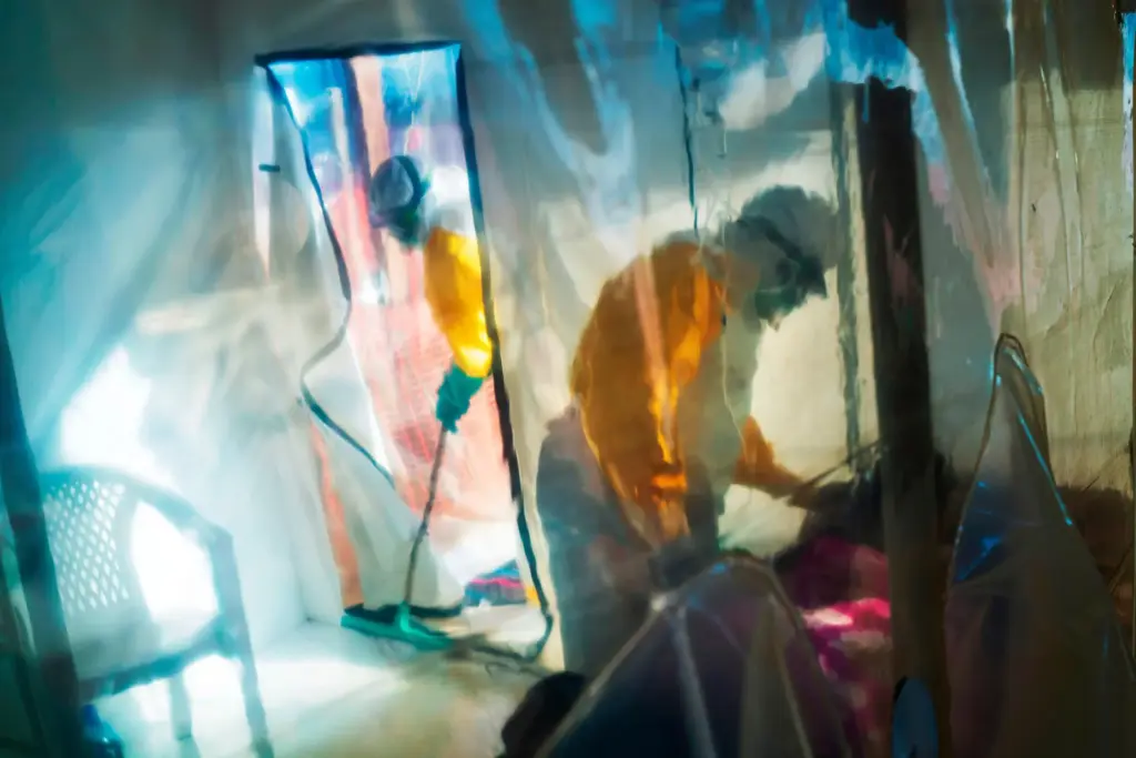 Health workers wearing protective suits tend to an Ebola victim