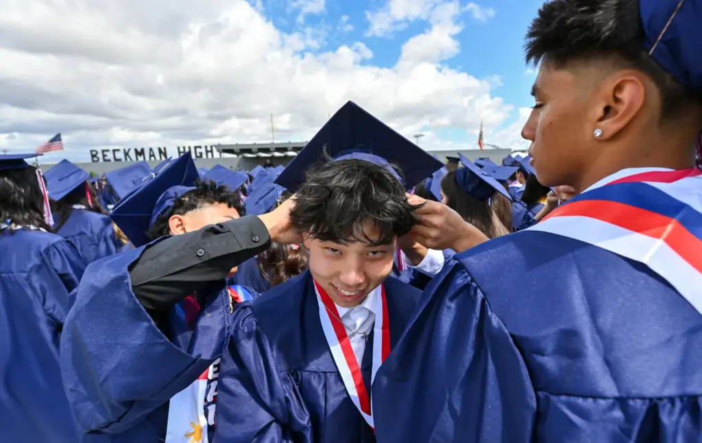 Jason Lee gets help adjusting his cap during the commencement...