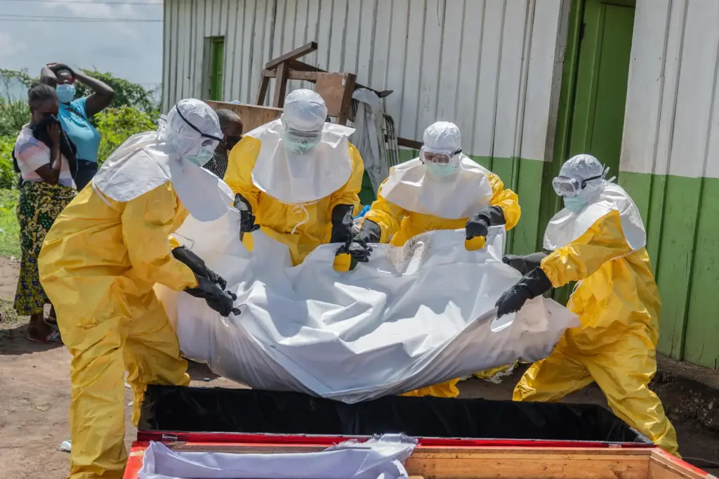 Red Cross workers carry the body of a person who died of Ebola into a coffin.