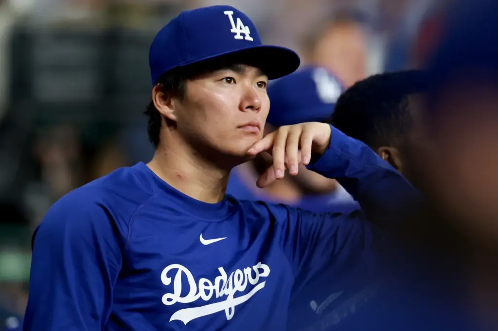 Dodgers starting pitcher Yoshinobu Yamamoto looks on from the dugout...
