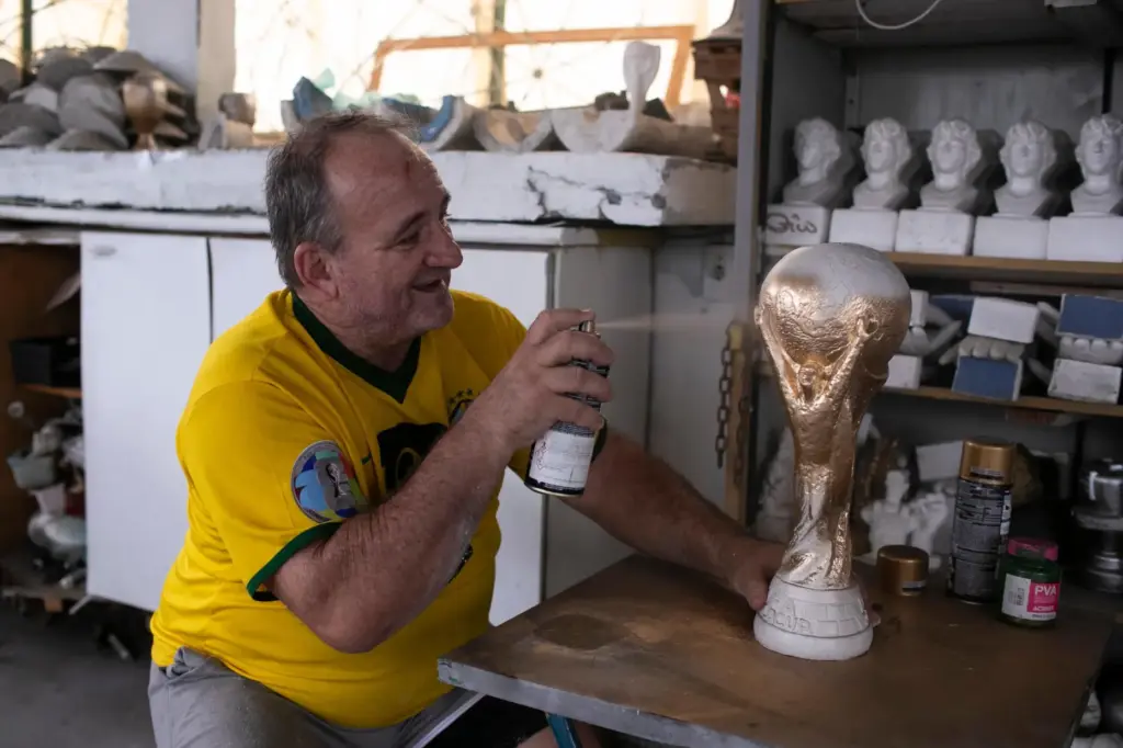 Jarbas Meneghini Carlini sprays a FIFA World Cup trophy replica he made.