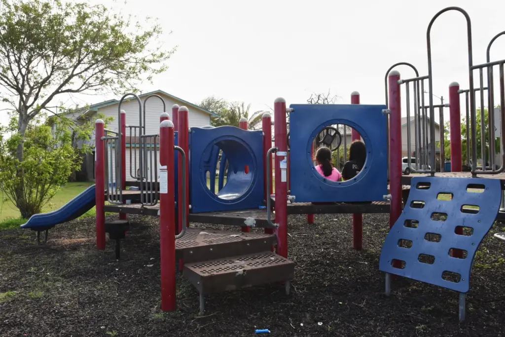 Two sisters play in a neighborhood playground that sits mostly vacant.
