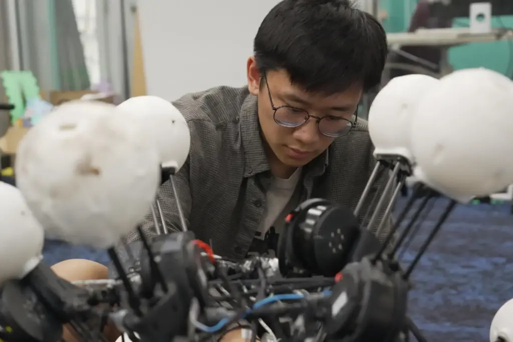 Jiaxun Liu, a Ph.D. student, works on a robot named...