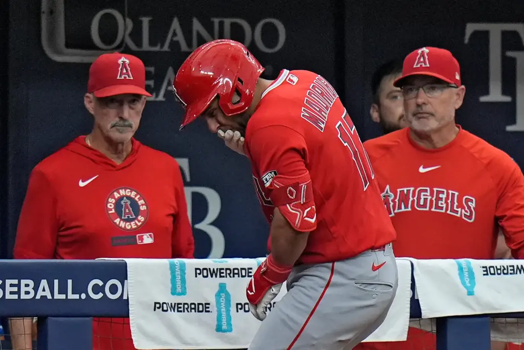 Angels’ Nick Madrigal, center, reacts after getting hit by a...