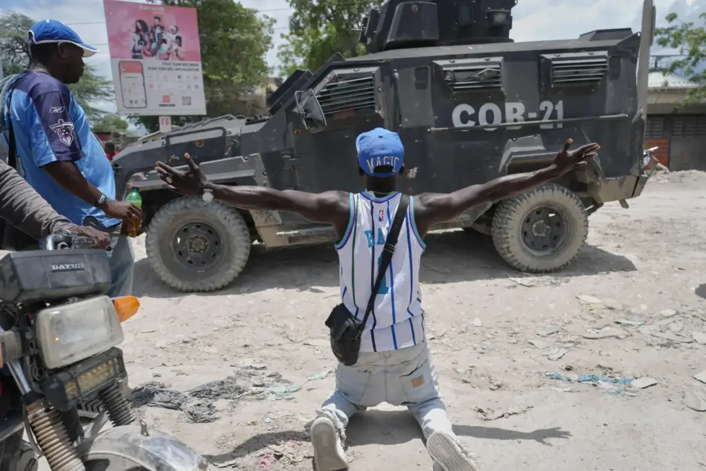 A resident of Cité Soleil kneels before a police armored...