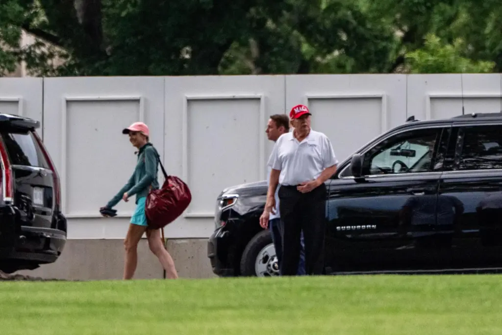 President Donald Trump with White House aide Natalie Harp walks to the White House.