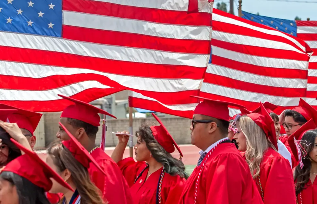Graduates waves to the crowd as the march into the...