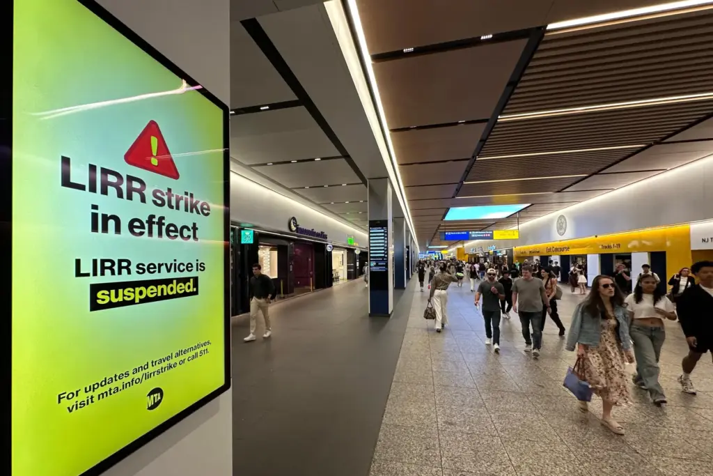 People walk past a sign board at Penn Station about the LIRR strike.