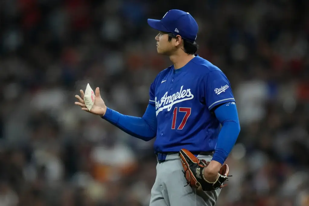 Dodgers starting pitcher Shohei Ohtani tosses the rosin bag between...