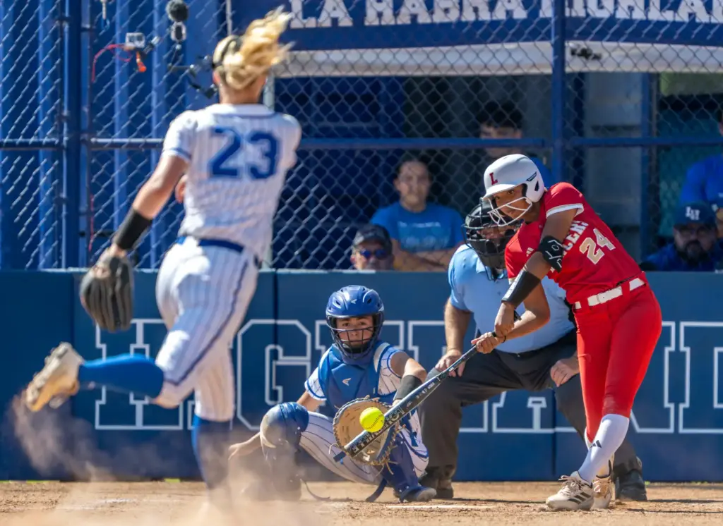 Orange Lutheran outfielder Eliza Johnson hits a pitch thrown by...