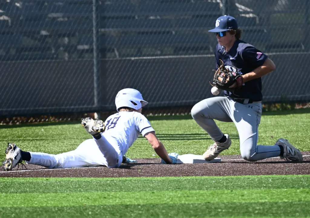 Henry Mann (18) of Newport Harbor slides safely back to...