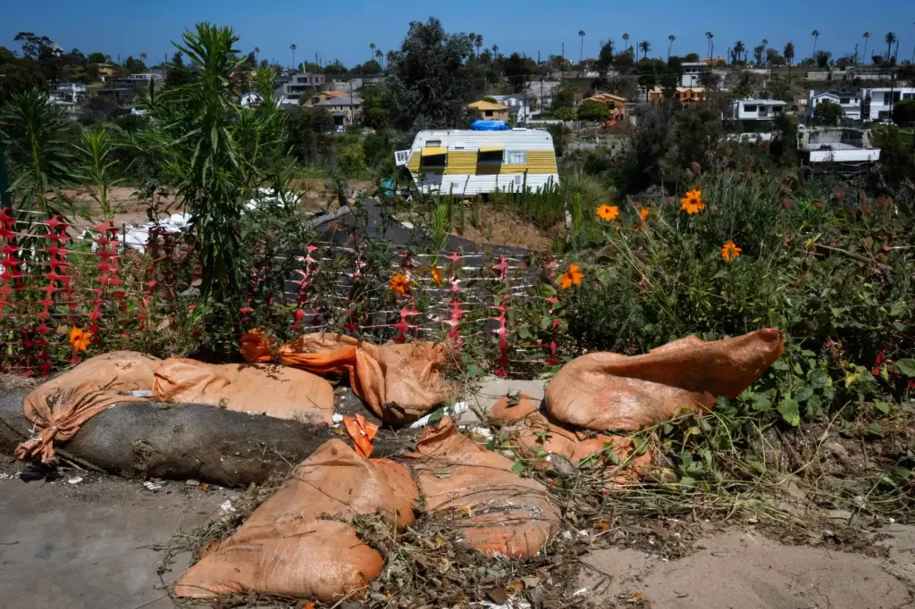 Sand bags and storm barriers lay along a lot on...