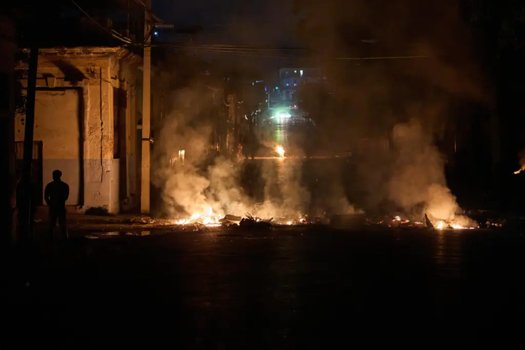 People look at a barricade set up by residents protesting against prolonged power outages.