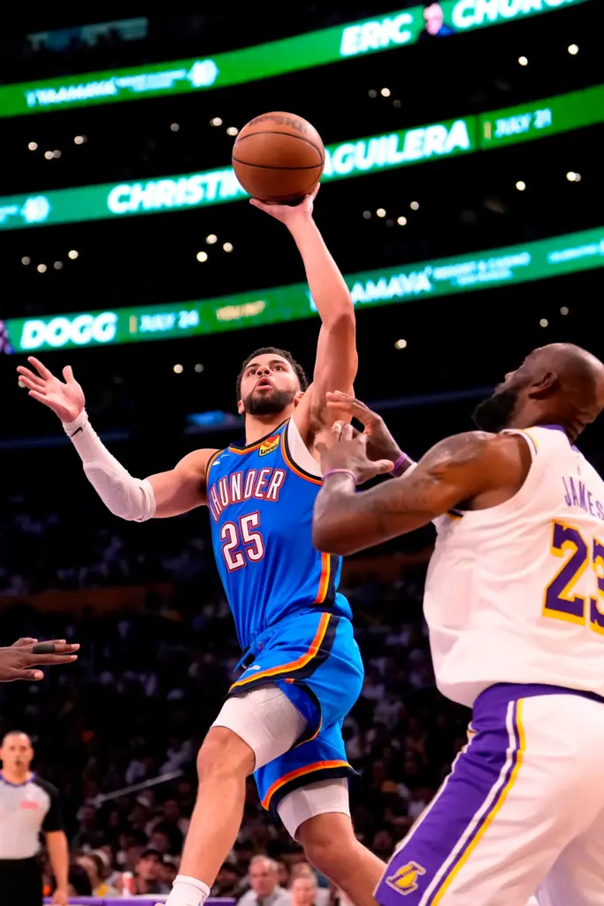 Oklahoma City Thunder guard Ajay Mitchell, left, shoots as Lakers...