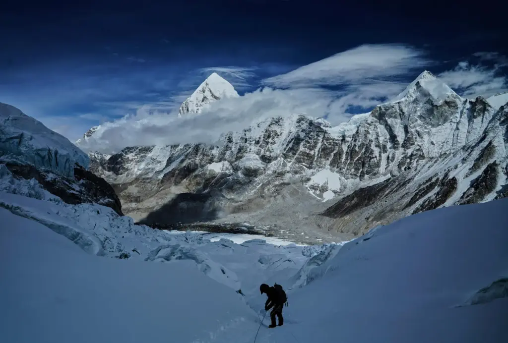 Mount Pumori, center left, looms in the background as a mountaineer negotiates Khumbu Icefall