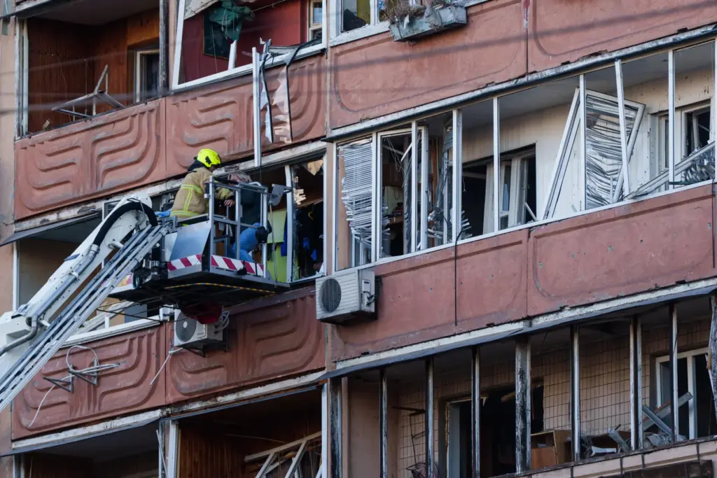 A rescuer evacuates a woman from a balcony of a house damaged after a Russian strike.