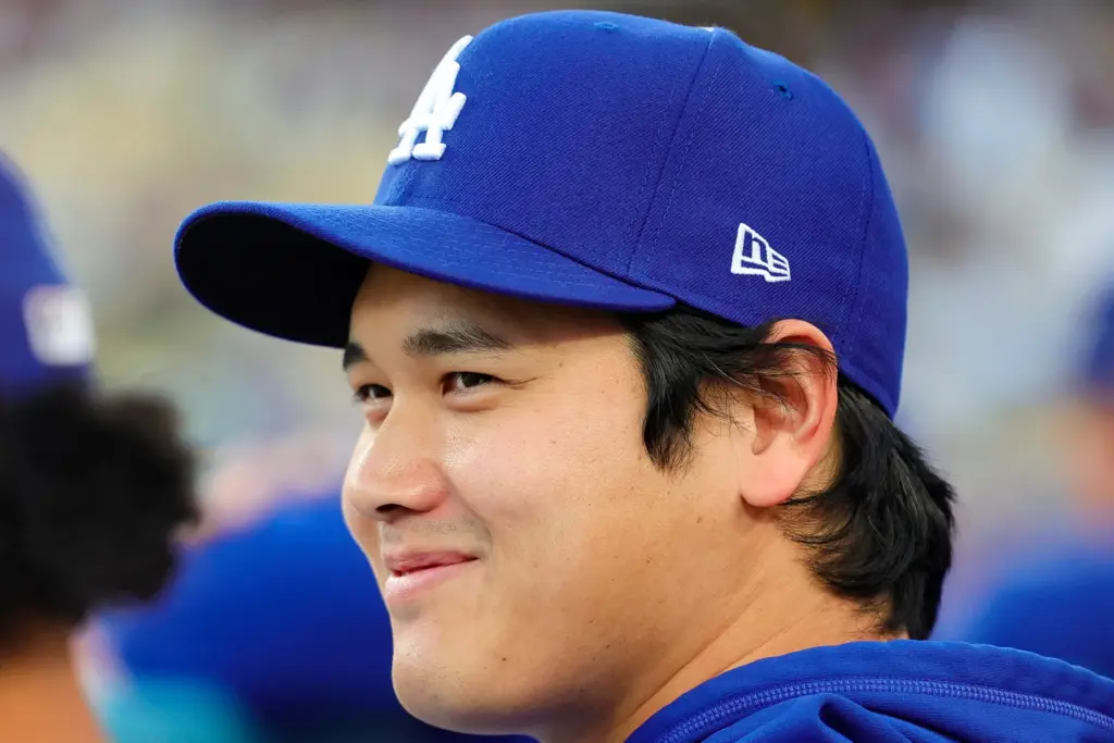 Dodgers star Shohei Ohtani reacts while sitting in the dugout...
